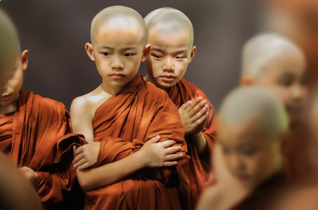 Two young Buddhist monks with shaved heads, wearing traditional orange robes