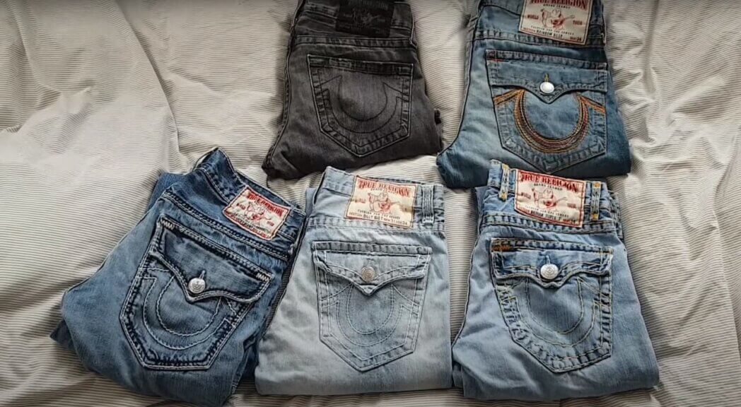 five pairs of different True Religion jeans laying folded on a white background