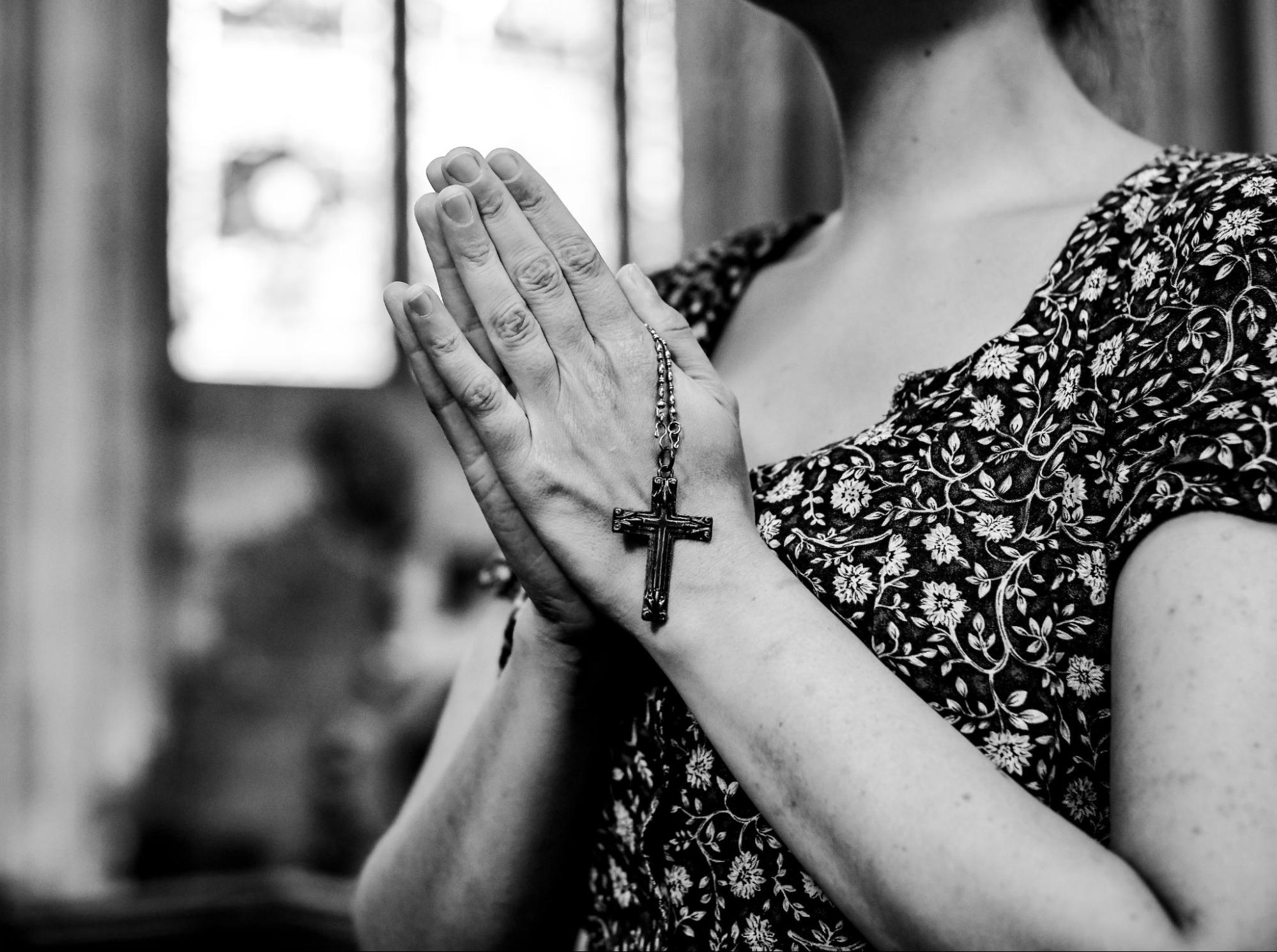 a catholic woman praying with a rosary at the church