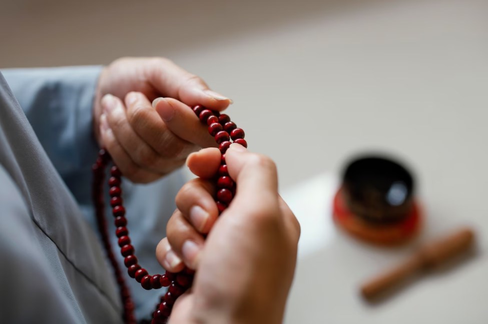 a high angle of woman’s hands holding beads and meditating