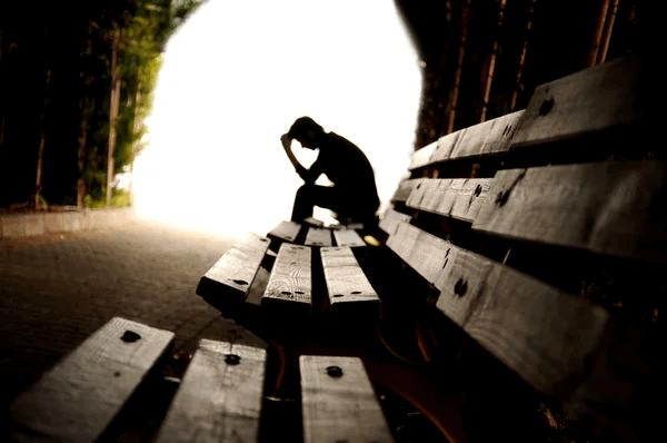 a sad man sitting on a bench