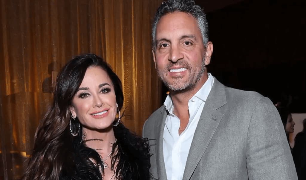Mauricio Umansky in a gray suit and his wife standing straight and smiling