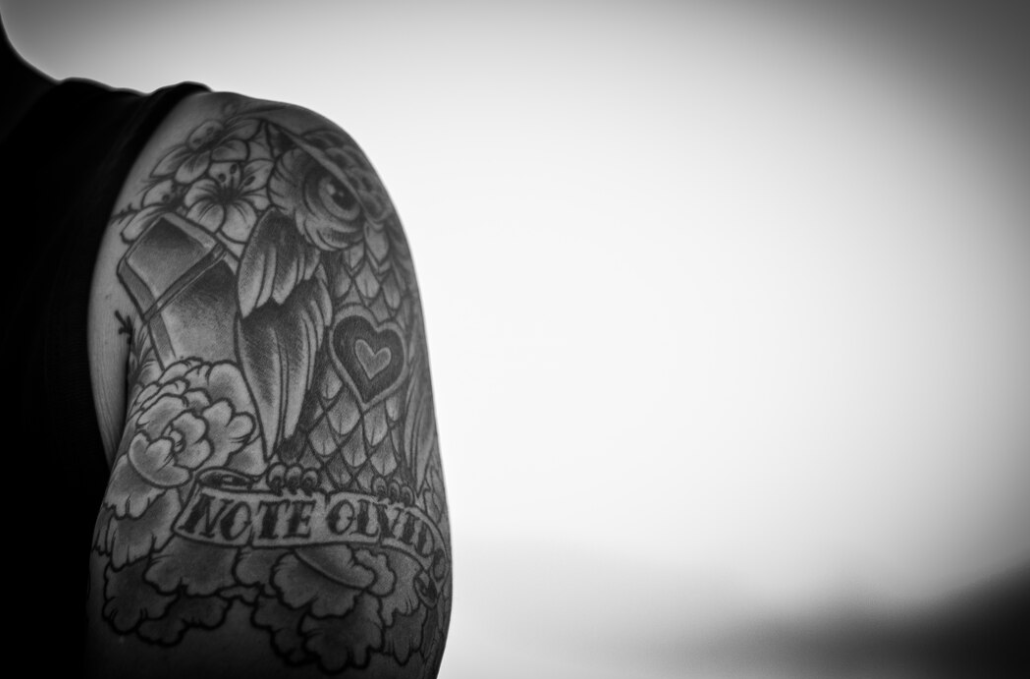 A black and white photo of an arm tattoo featuring a heart and flowers