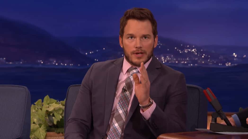 Chris Pratt speaking and gesturing, dressed in a suit on a talk show