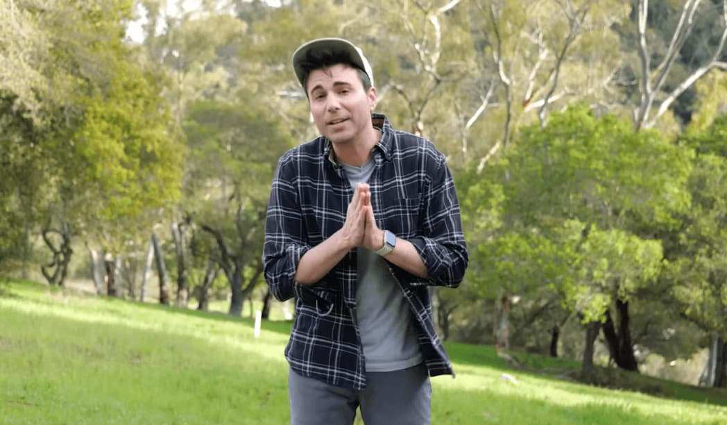 Mark Rober in hat and shirt standing in the park with trees