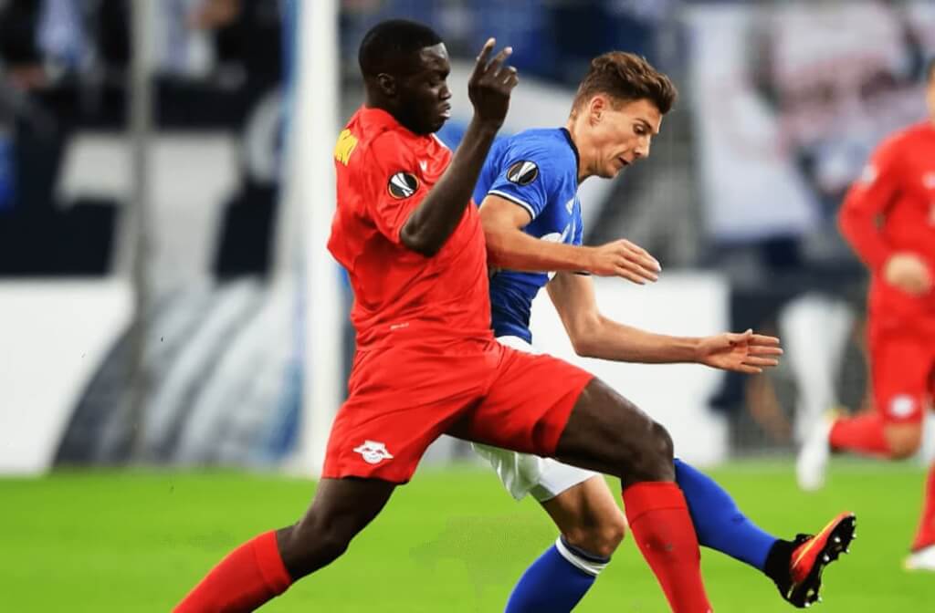 upamecano in red sports clothing with football players in blue uniform on the field during the gameplay