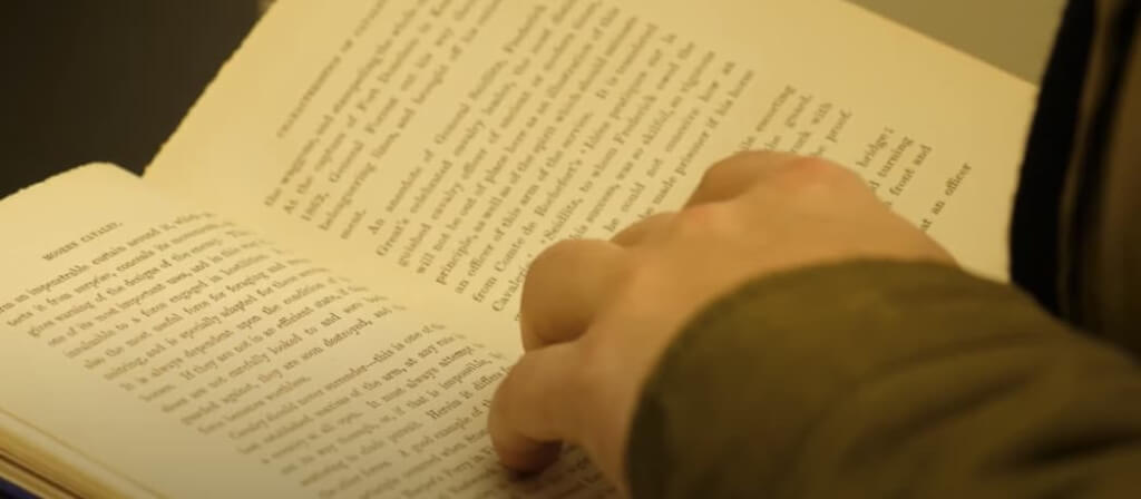 Book with a hand resting on top of open pages.