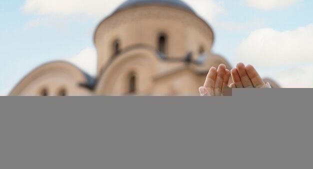 Hands clasped together against the background of a church