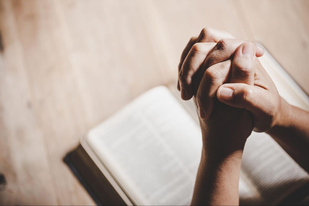 Two hands in a praying position over the book