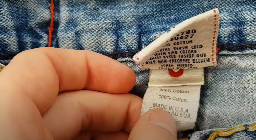 a hand holding a label of the TR jeans with indicated materials and the country of origin